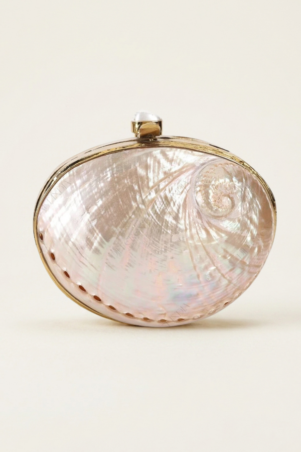 An oval clutch bag featuring a mother-of-pearl shell inlay with iridescent pink and gold tones, framed by gold-tone metal trim and a small top clasp, set against a plain off-white background.