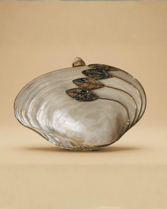 The Ormolu minaudière — front pearly mother-of-pearl oval clutch with gilded brass leaf motifs tracing the edge, ornate handcrafted evening bag.