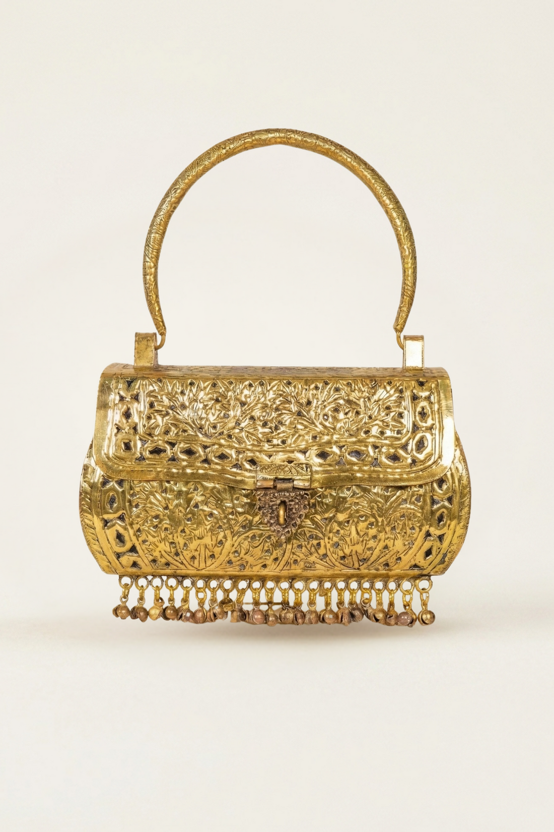 An ornate gold-toned metal handbag with intricate filigree cutouts, a curved top handle, and a dangling beaded fringe along the bottom, shown against a plain light background.
