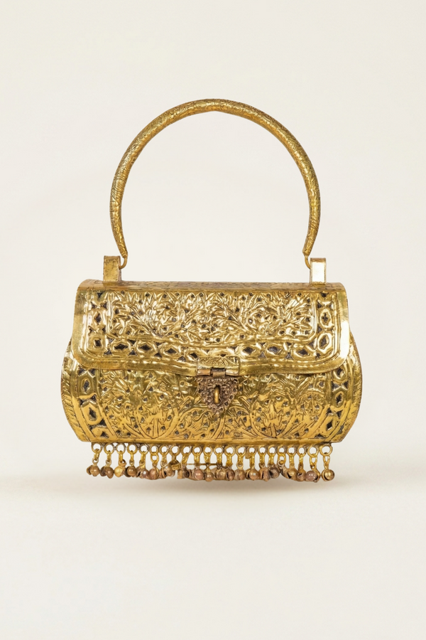 An ornate gold-toned metal handbag with intricate filigree cutouts, a curved top handle, and a dangling beaded fringe along the bottom, shown against a plain light background.