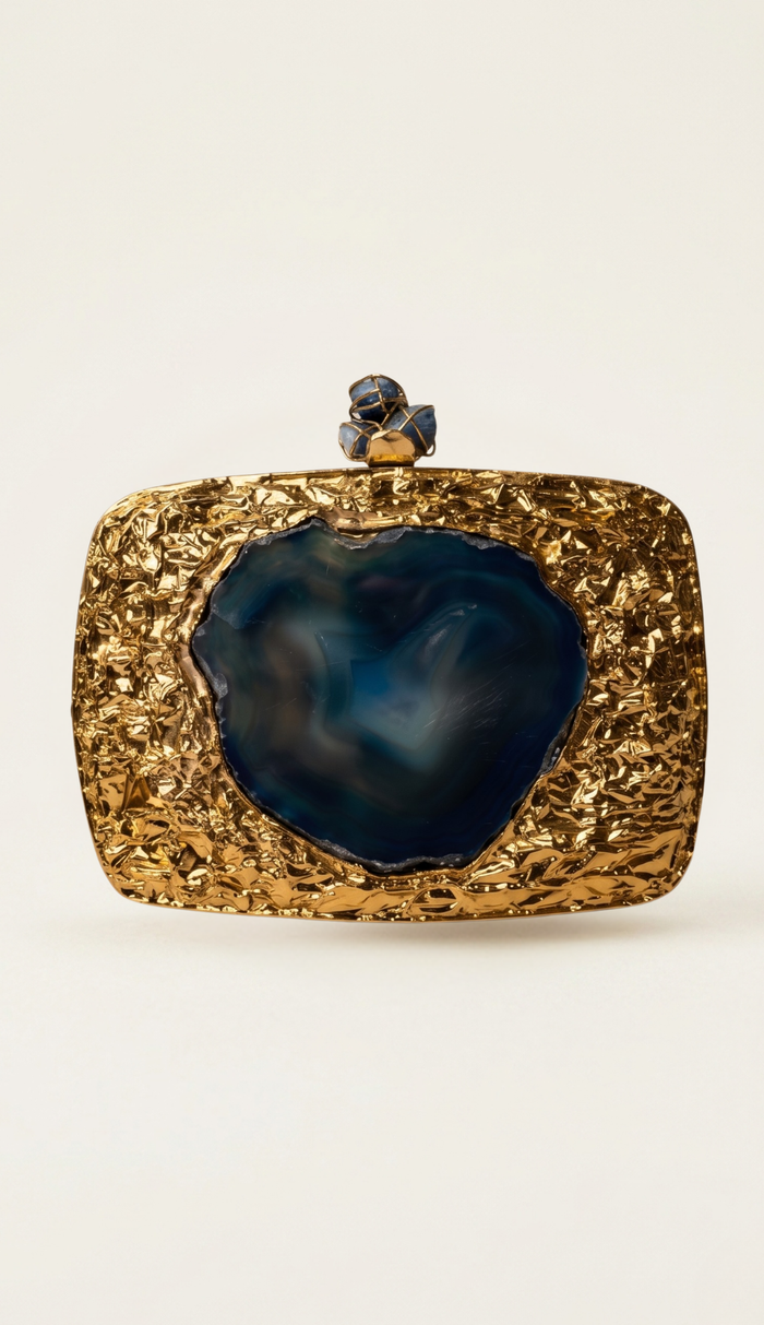 The Geode brass minaudière carried by a model, styled for evening