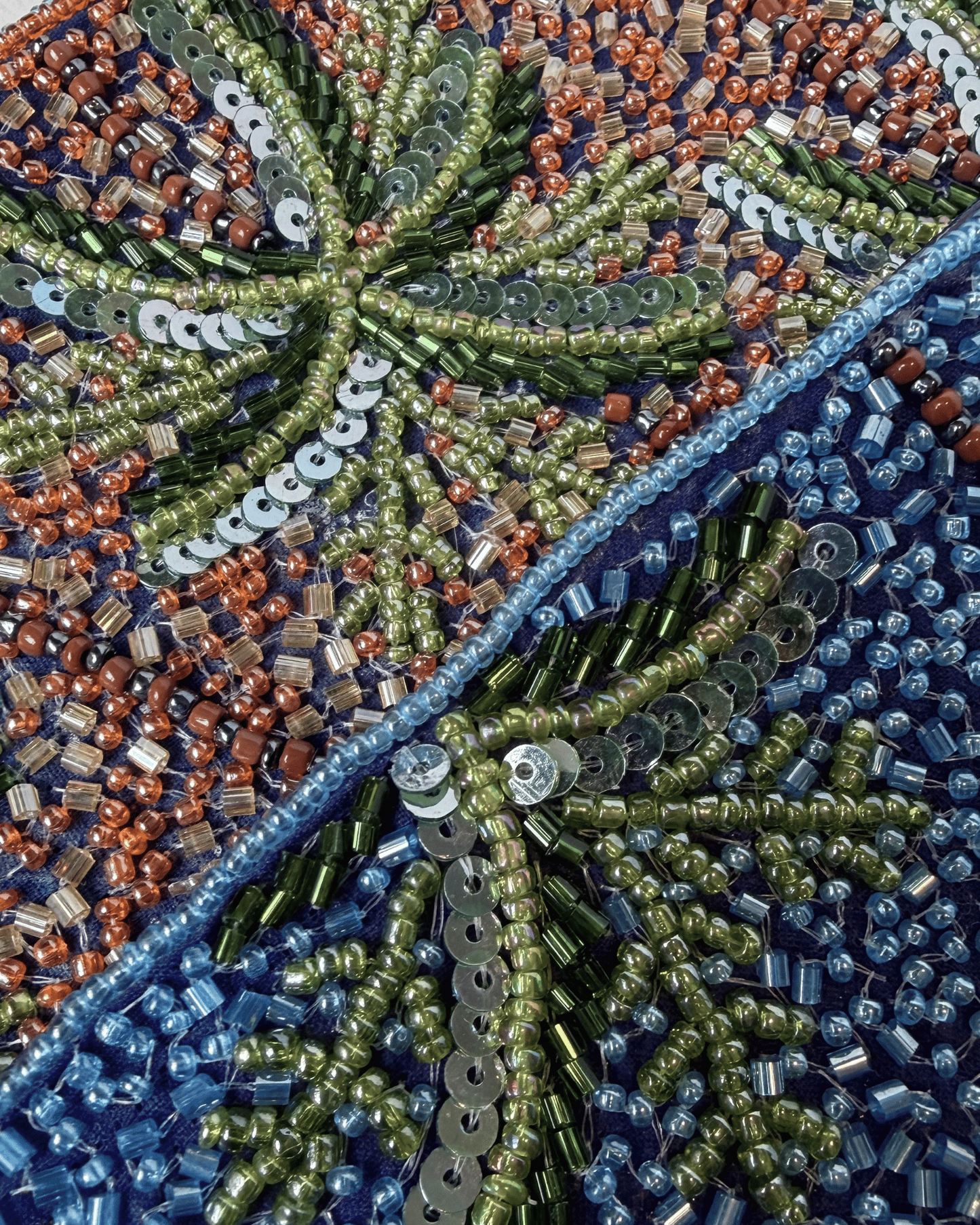 The Palma — close-up of the intricate beadwork and sequins forming palm fronds in green, rust and blue, showcasing the artisan handcraft.