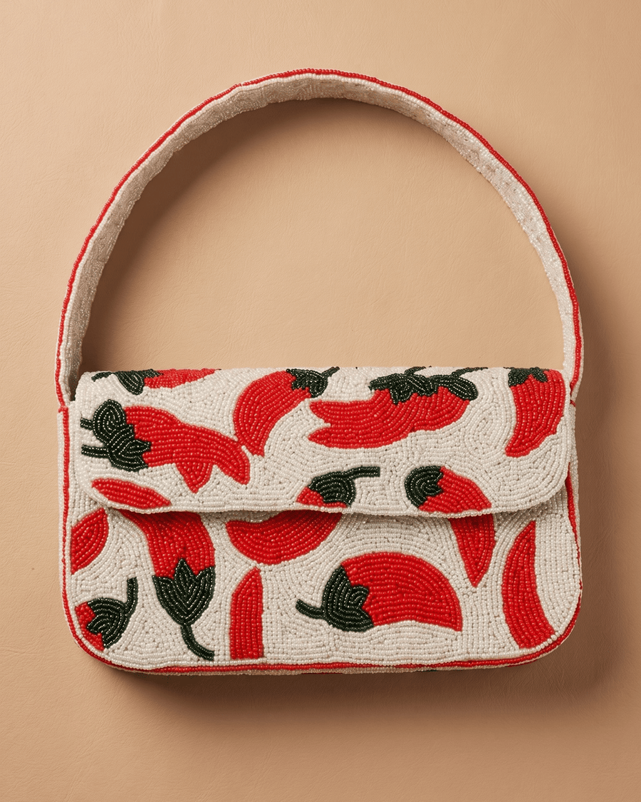 Front of The Cayenne: a cream seed-bead flap bag covered in red beaded chilies with green stems and a curved top handle.