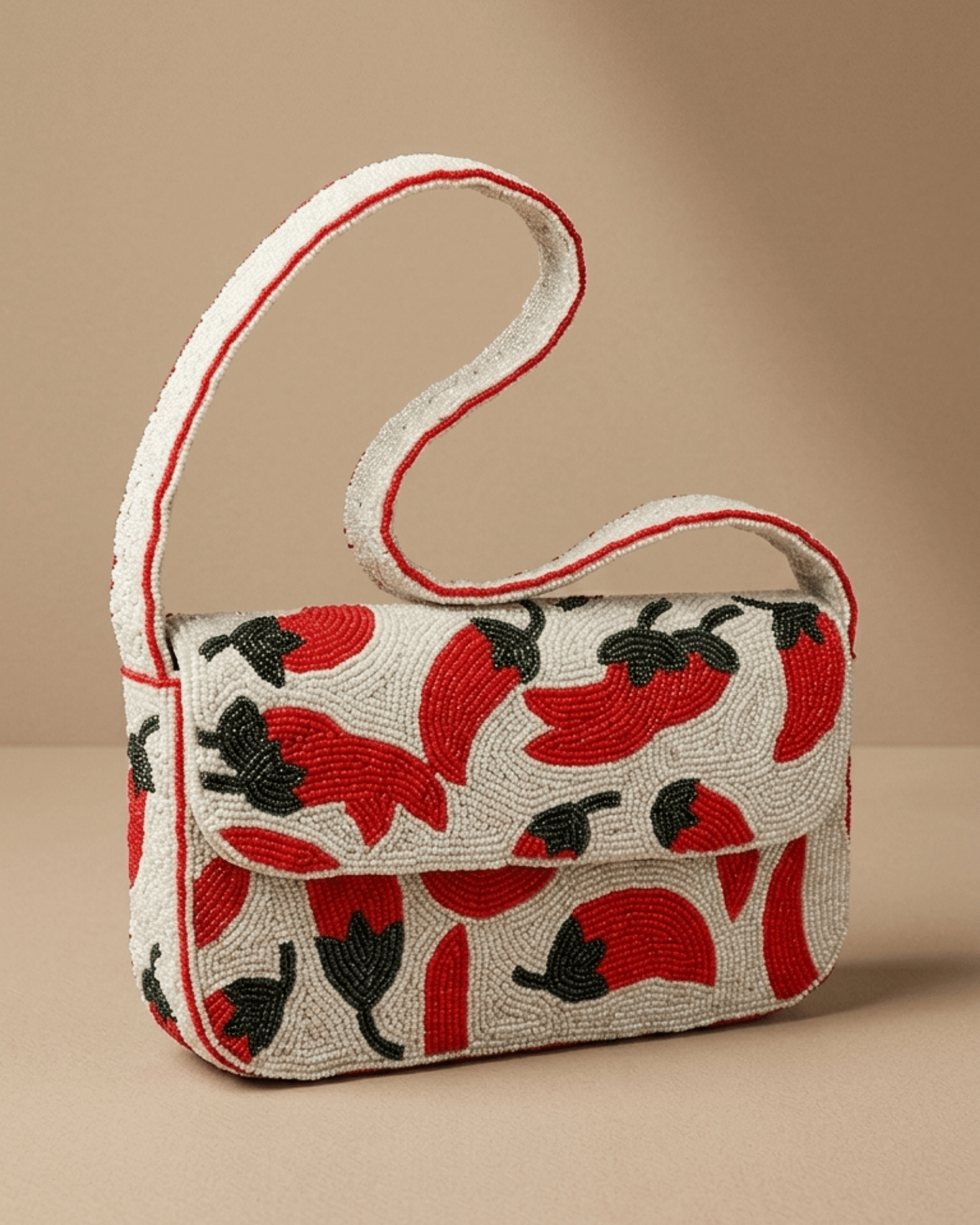 Three-quarter view of The Cayenne hand-beaded chili-pepper shoulder bag with its slim strap looped behind it.