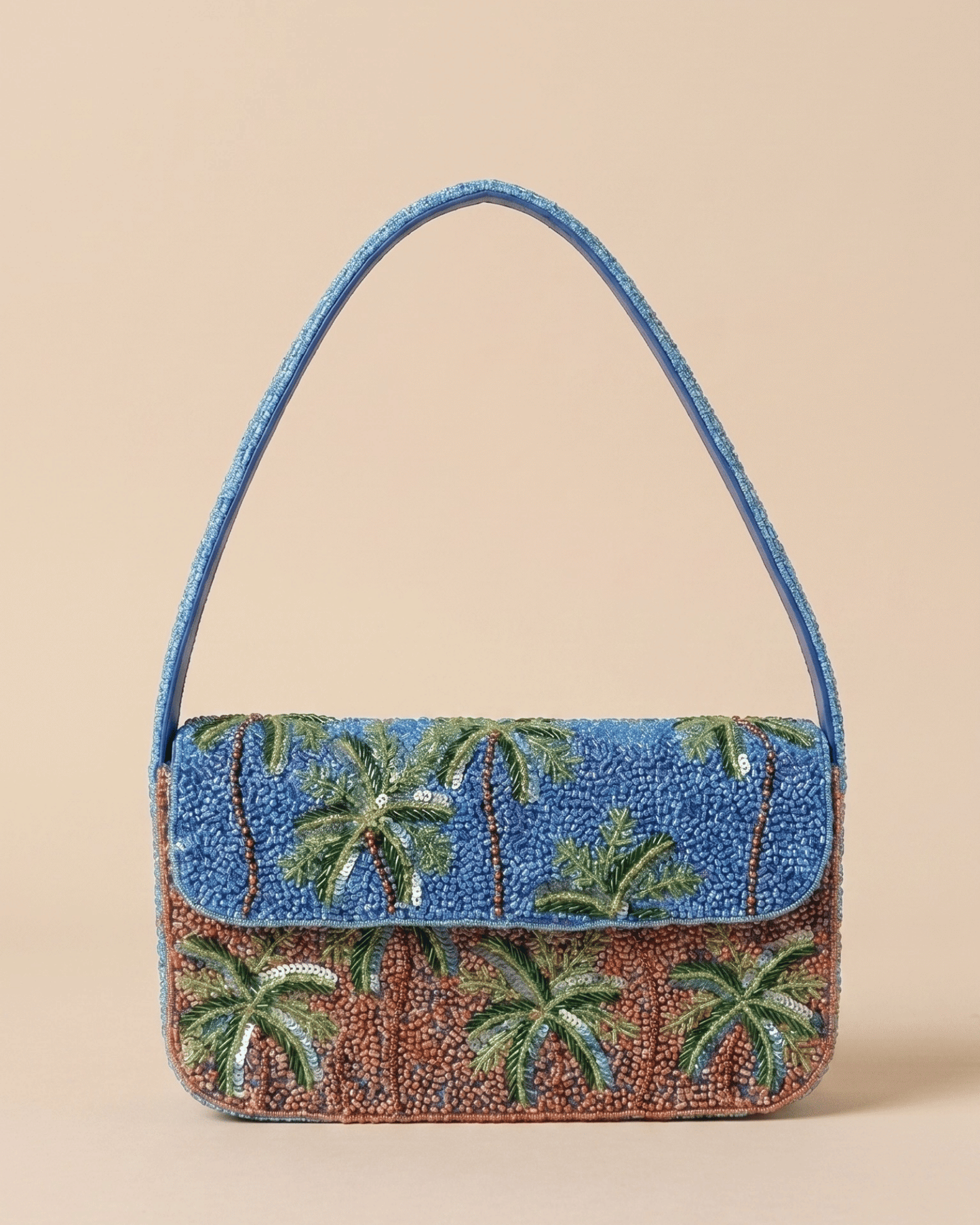 The Palma — front of the hand-beaded shoulder bag with green palm trees on a blue sky over terracotta sand, with a slim beaded top handle.