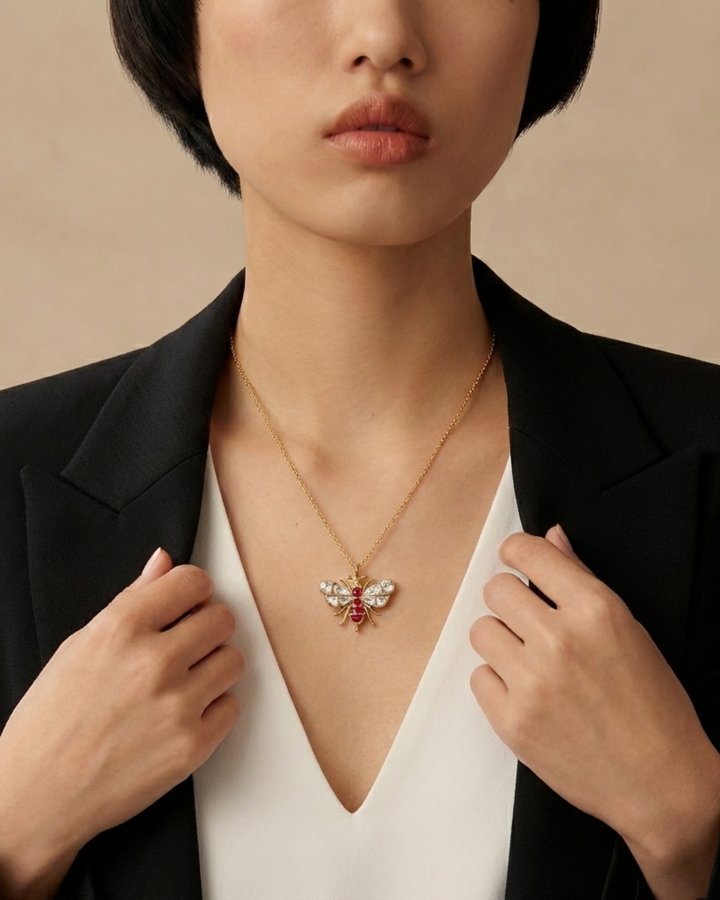 Model wears The Imperial Bee Pendant, a gold bee set with ruby and crystal stones, on a fine chain.