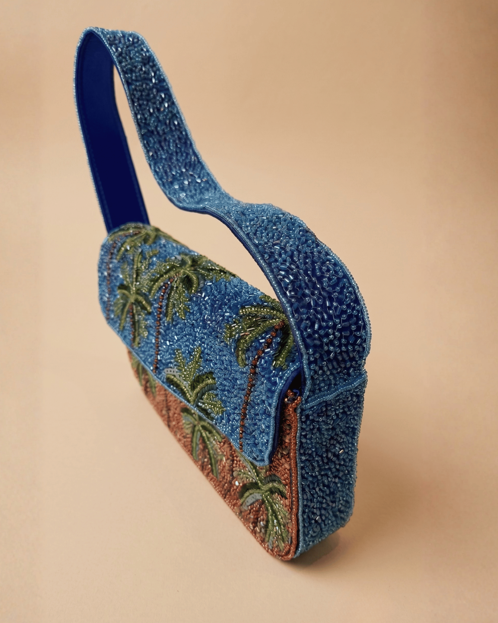 The Palma — three-quarter view of the beaded palm-tree bag showing its boxy shape, blue and terracotta beadwork and looped top handle.