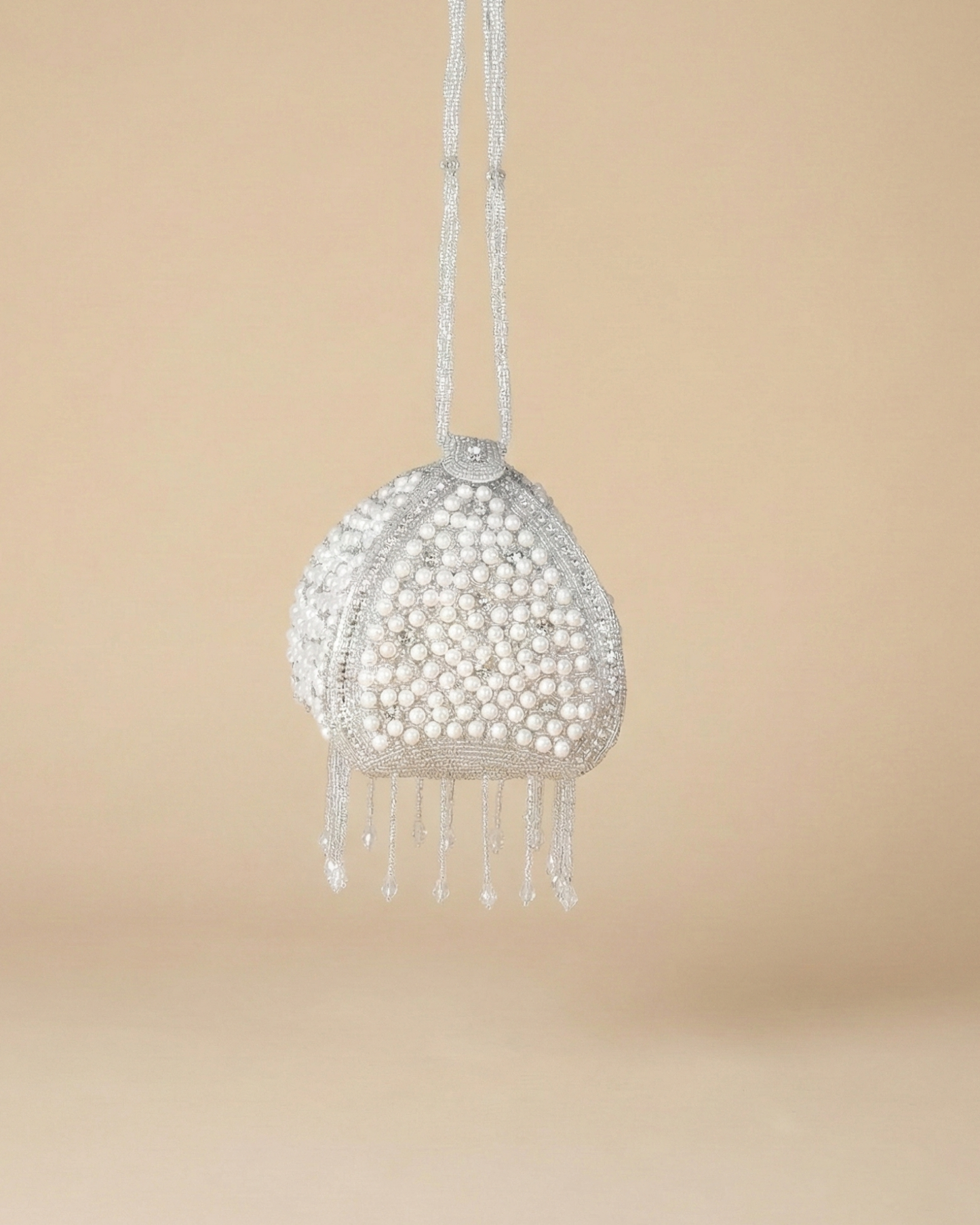 Front of The Luna Pearl Prism showing its pearl-and-crystal beadwork and dangling beaded fringe on a drawstring cord.