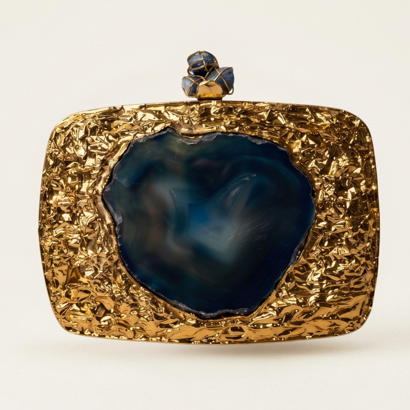 The Geode brass minaudière carried by a model, styled for evening