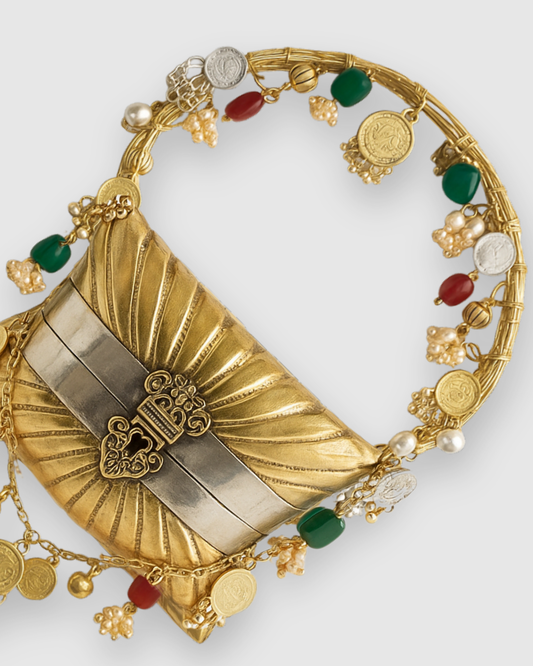The Nomad's pleated gold-and-silver brass body with an ornate filigree clasp, framed by a ring handle strung with coins, agate beads and pearls.