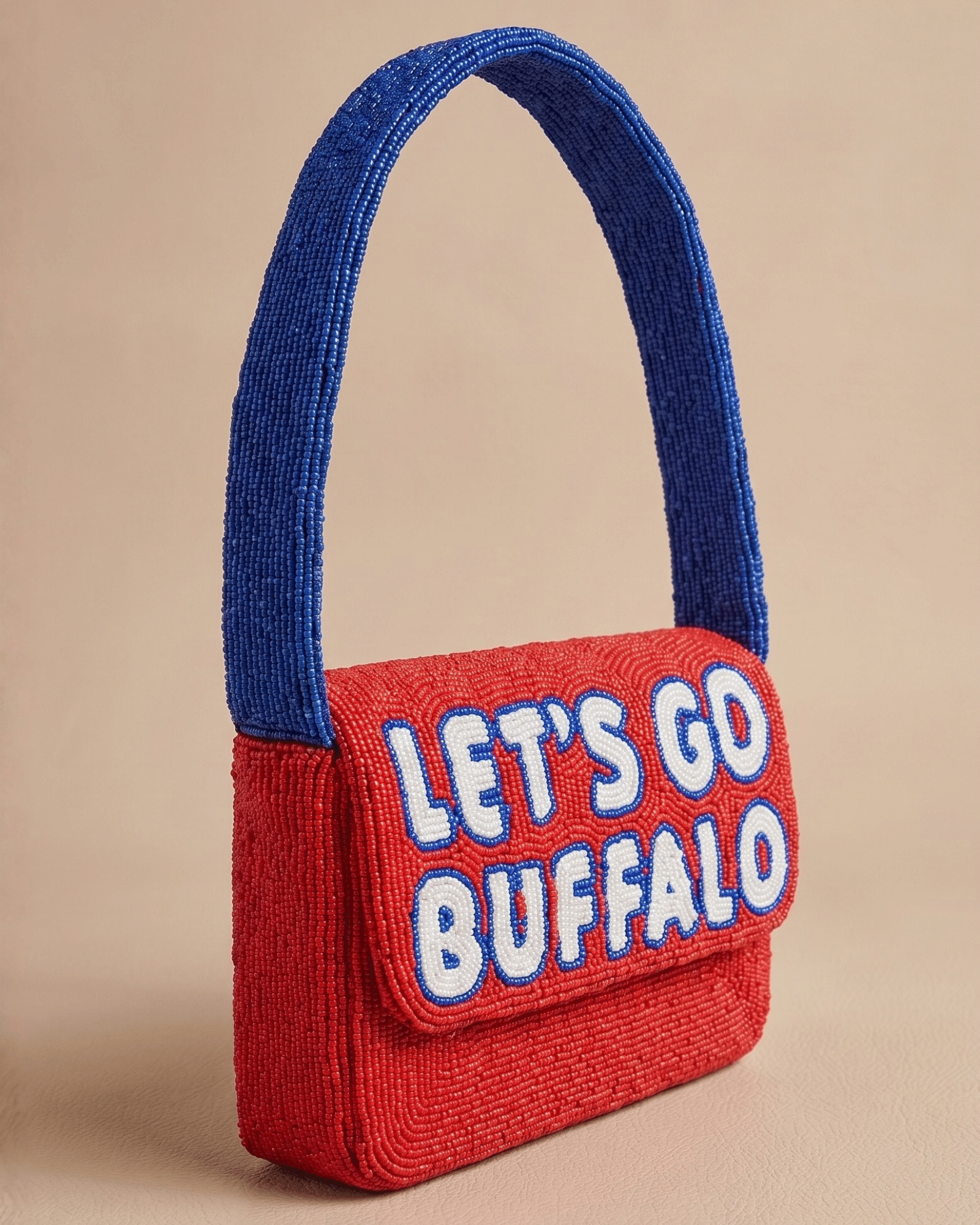 The Rally Buffalo Edition — three-quarter front view of the red beaded ‘Let’s Go Buffalo’ handbag with raised lettering and blue handle.