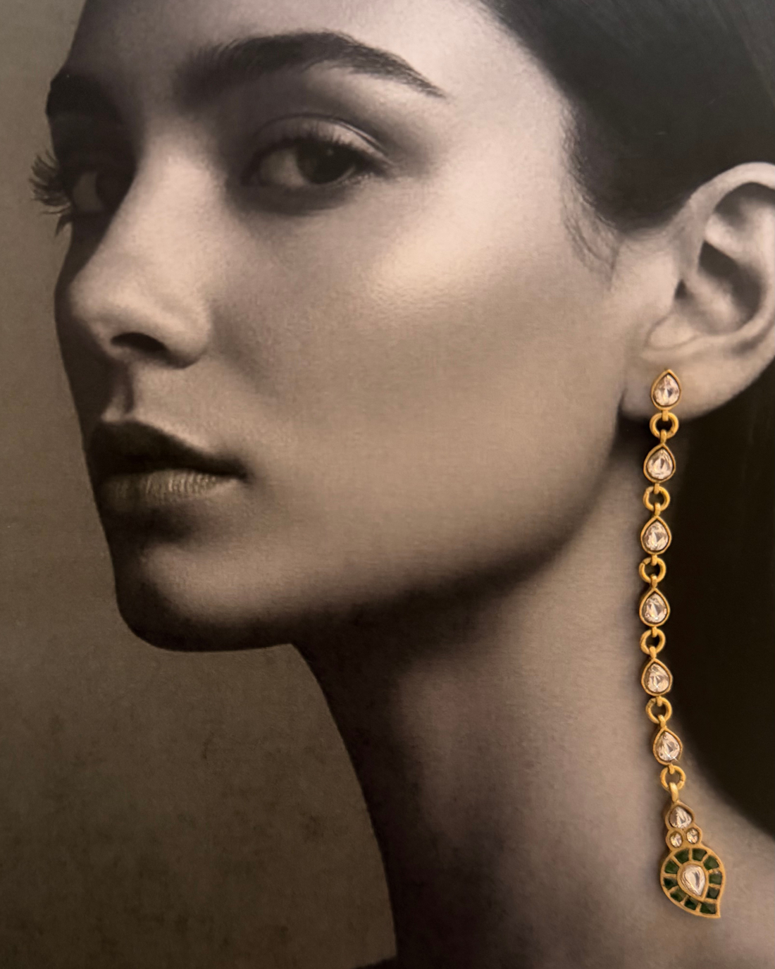 The Emerald-Tip Cascade Earrings held by a model against a neutral outfit