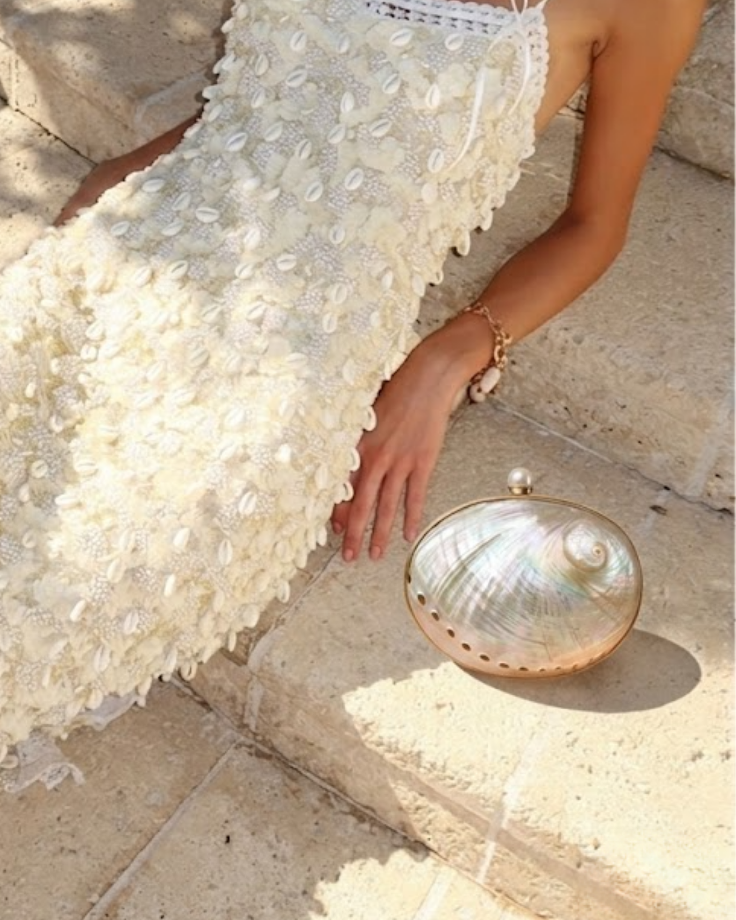 The Éclat shell minaudière — detail view of the iridescent abalone-shell clutch with polished gold frame and pearl clasp